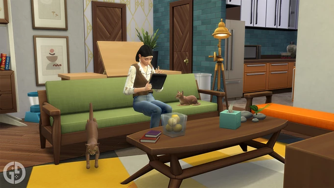A Sim sat on a couch using a tablet surrounded by two cats