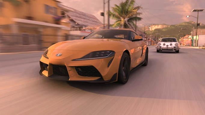 An orange car races ahead of a white car.