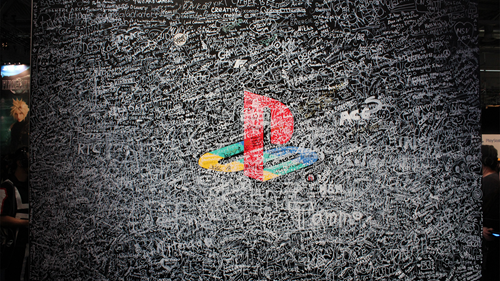 A wall at Gamescom 2019 adorned with the PlayStation logo, covered in signatures in white.