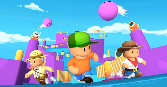 Characters run away from giant bowling balls in Stumble Guys.