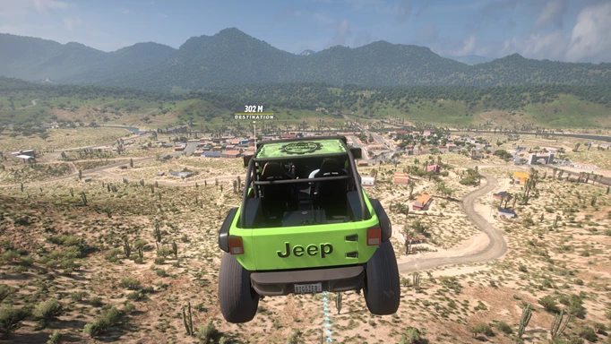 A green jeep flies over a green landscape with mountains in the distance.