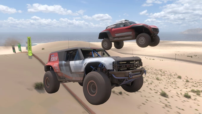 Two jeeps fly through the air over sand dunes.