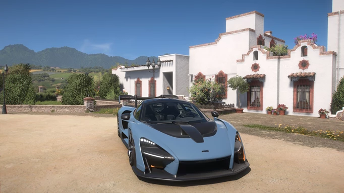 A blue car sits in front of a white villa.