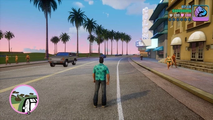 A man walks through a street with palm trees.