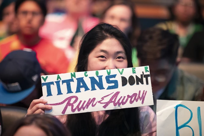 Woman holding up a sign that reads Vancouver Titans don't RunAway
