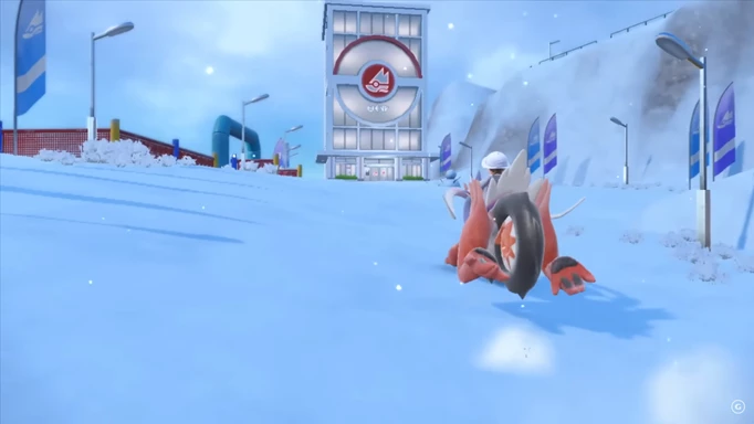 The player approaching a Pokemon Gym in a snowy area, on the back of their legendary Pokemon
